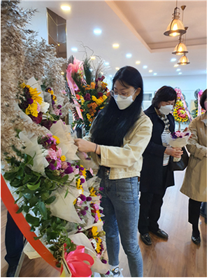 신화환이 전시되고 있는 가운데 하객들이 꽃을 가져가고 있다.