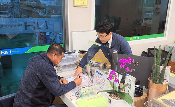 지난 23일 경북 성주 초전농협 자재판매장을 찾은 한 농업인이 농협 필름 담당자의 설명을 들으며 하우스필름 예약구매 신청서를 작성하고 있다.