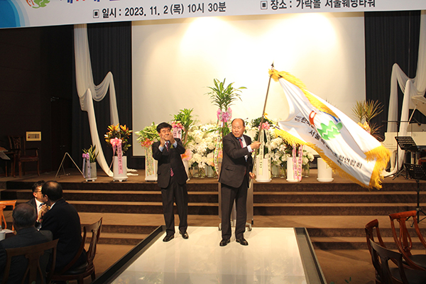 이한정 한중연 서울지회장이 엄주헌 전임 회장으로부터 지회 깃발을 전달받고 힘차게 힘들고 있다.