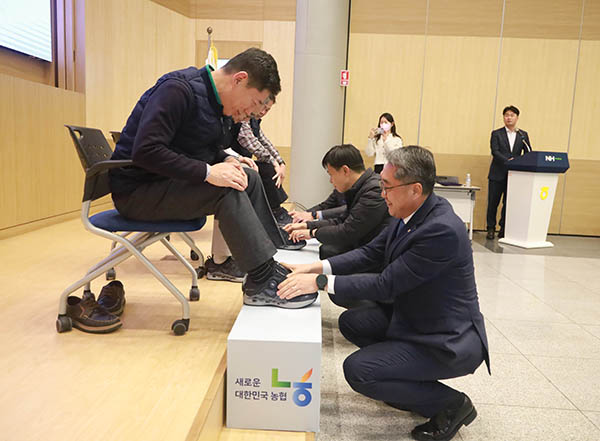 회의에 참석한 염기동 대표이사가 사무소장의 신발 끈을 매어주고 있다.