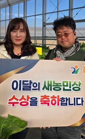 목진서·김경 조합원 부부가 농원에서 3월 ‘이달의 새농민상’ 수상기념판을 들고 기념촬영을 하고 있다.